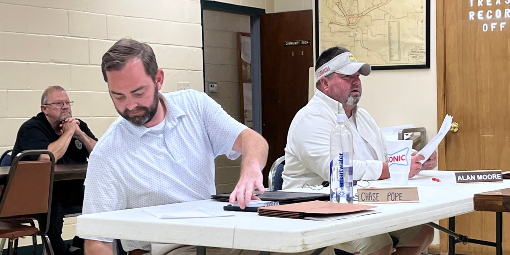 Glenwood Police Chief Greg Harmon (back left) listens while city council members Chase Pope and Alan Moore speak during Monday’s meeting. Photo: Michael Hibblen