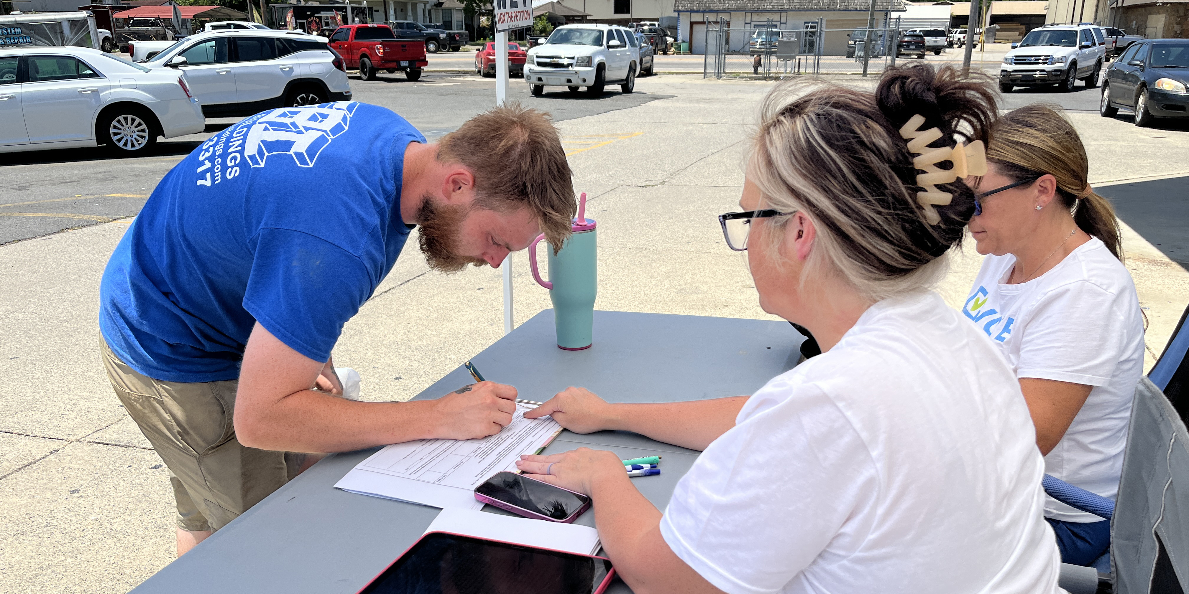 Devin York signed a petition at a table staffed by Tasha Harris and Emily Hamilton in front of Wright’s Food Center in Glenwood on July 10. Photo: Michael Hibblen